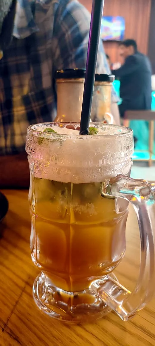 An iced tea with lemon in a glass mug on a café table.